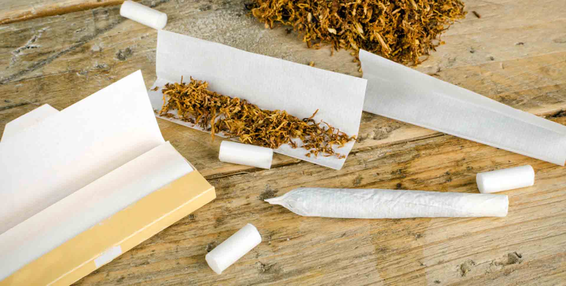 Cigaretové papieriky, tabak, rolovačka a ubalený joint