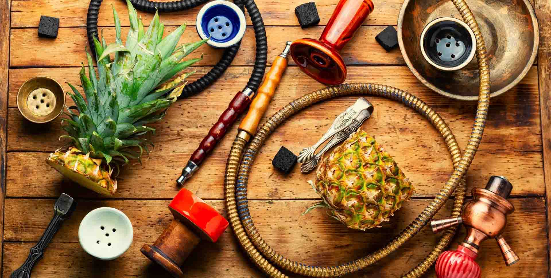 Komponenty vodnej fajky: korunky, hadice, kliešte, uhlíky a prekrojený ananás